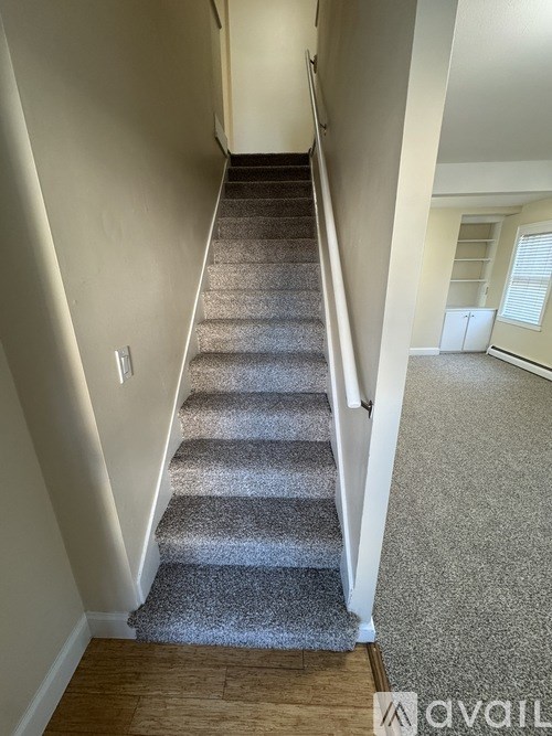 A staircase with a carpeted runner and white walls.