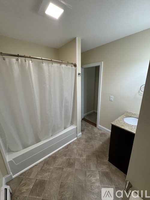 A bathroom with a shower curtain and a sink.