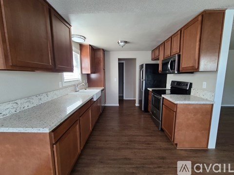 A kitchen with brown cabinets and a black refrigerator.