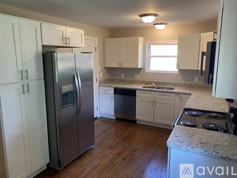 A kitchen with a stainless steel refrigerator and white cabinets.