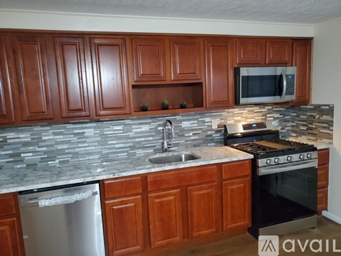 A kitchen with wooden cabinets and a stone backsplash.