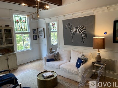 A living room with a white couch and a zebra painting on the wall.