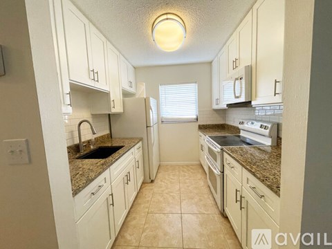 A kitchen with white cabinets and granite countertops.