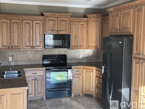 A kitchen with wooden cabinets and black appliances.