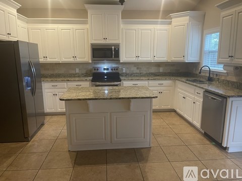 A kitchen with white cabinets and a granite countertop.
