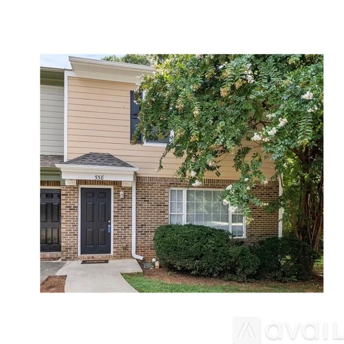 A house with a black front door and a tree in front.