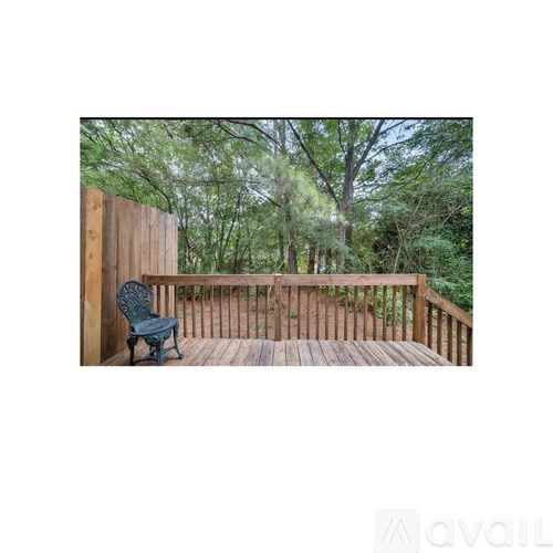 A wooden deck with a chair and trees in the background.