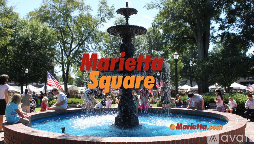 A fountain in the middle of a park with the words "Marietta Square" written across it.