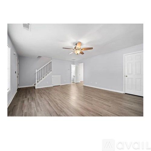A spacious room with a ceiling fan and wooden flooring.