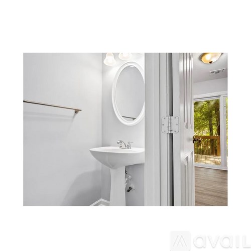 A bathroom with a white sink and a round mirror.