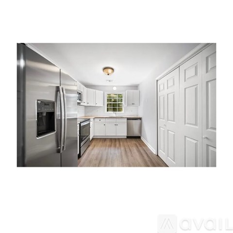 A kitchen with white cabinets and a stainless steel refrigerator.