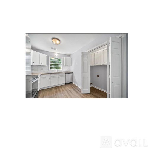 A kitchen with white cabinets and a wooden floor.