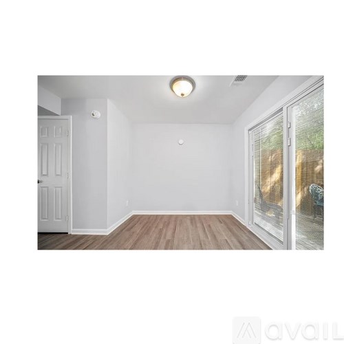 A room with a white door and a window with a view of trees.