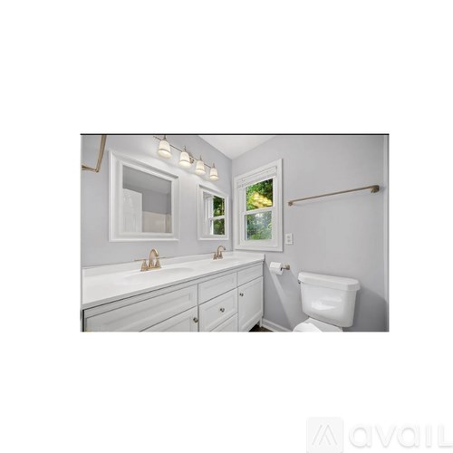 A white bathroom with a toilet, sink, and mirror.