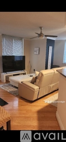 A living room with a beige couch and a ceiling fan.