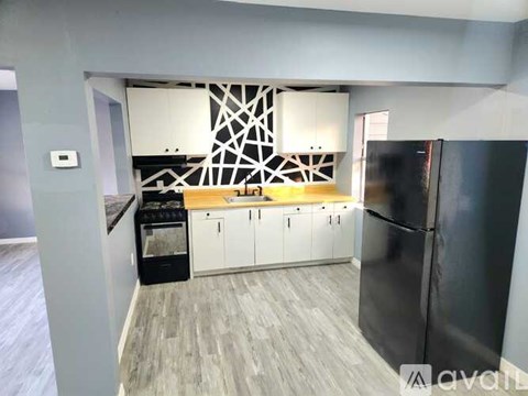 A kitchen with a black fridge and white cabinets.