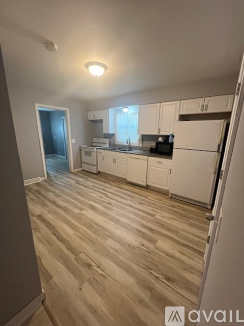 A kitchen with white cabinets and a wooden floor.
