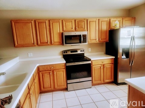 A kitchen with wooden cabinets and a black refrigerator.