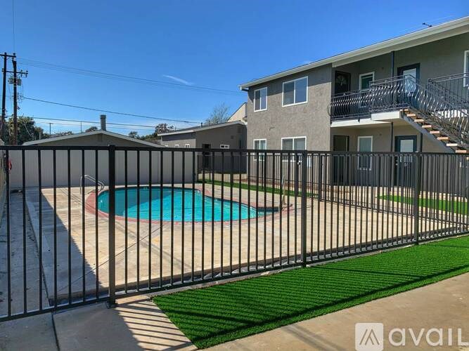 A black fence surrounds a small pool in a backyard.