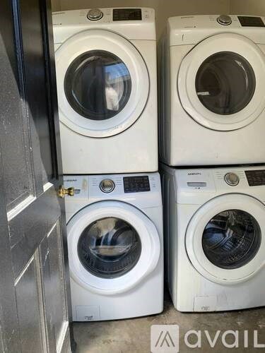 Four front load washing machines are stacked in a room.