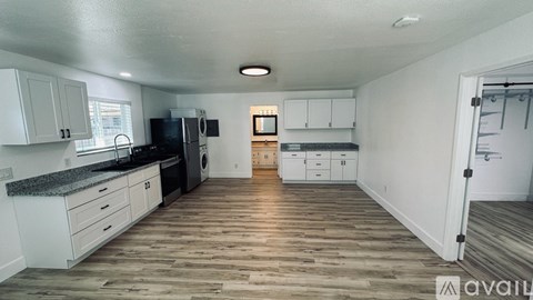 A kitchen with white cabinets and a wooden floor.