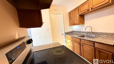 A kitchen with a stove top oven and wooden cabinets.
