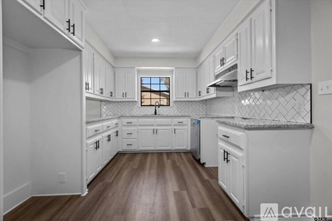 A kitchen with white cabinets and a wooden floor.