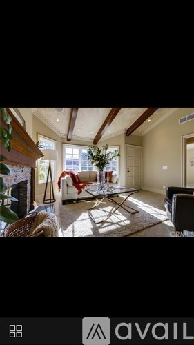 A living room with a couch, chair, and a table with a vase of flowers on it.