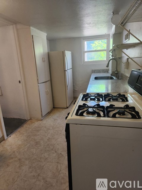 A kitchen with a stove, refrigerator, and cabinets.