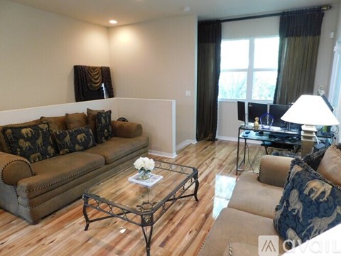 A living room with a brown couch and a glass coffee table.