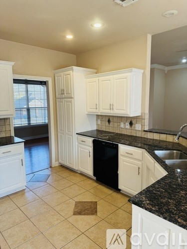 A kitchen with white cabinets and black countertops.