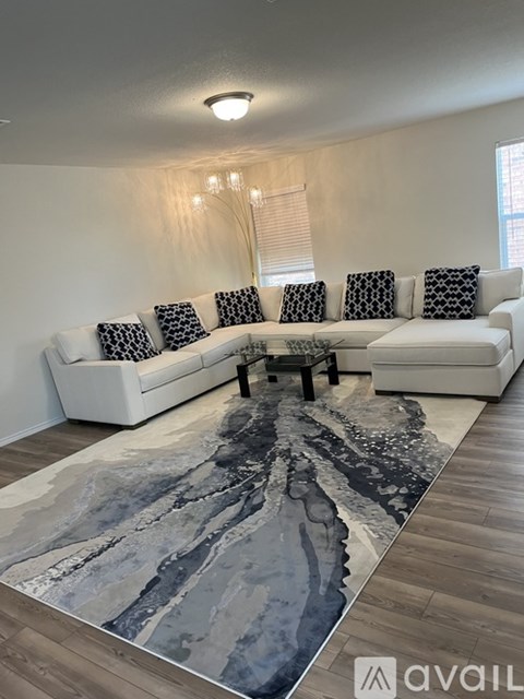 A living room with a white couch and a grey rug.