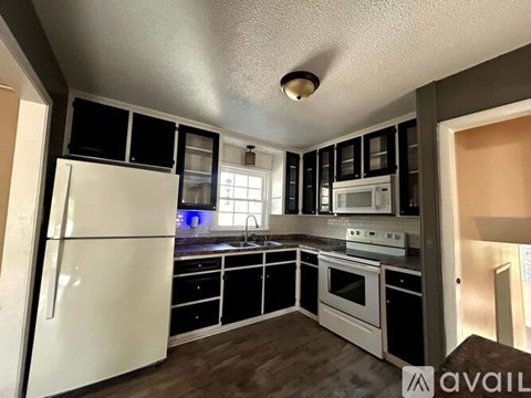 A kitchen with a white refrigerator and black cabinets.