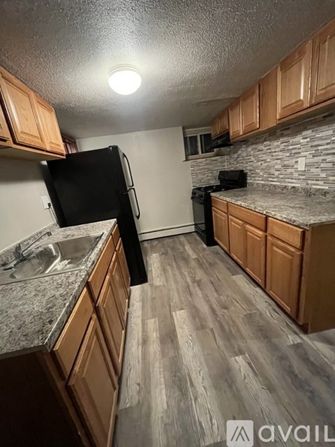 A kitchen with wooden cabinets and a black fridge.