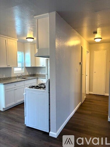 A kitchen with white cabinets and a white refrigerator.