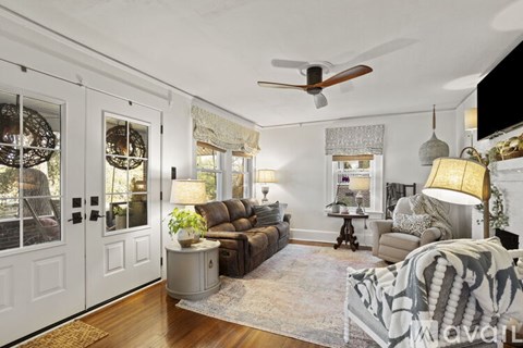 A living room with a brown couch and a ceiling fan.