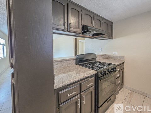 A kitchen with dark brown cabinets and a granite countertop.