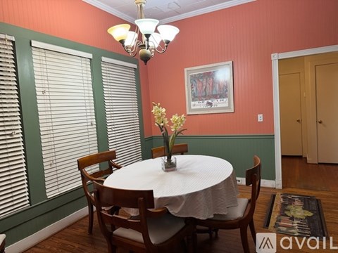 A dining room with a table set for two and a chandelier hanging from the ceiling.