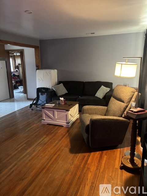 A living room with a brown couch, a chair, and a table with a lamp on it.