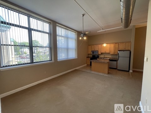 A spacious room with a kitchenette and large windows.