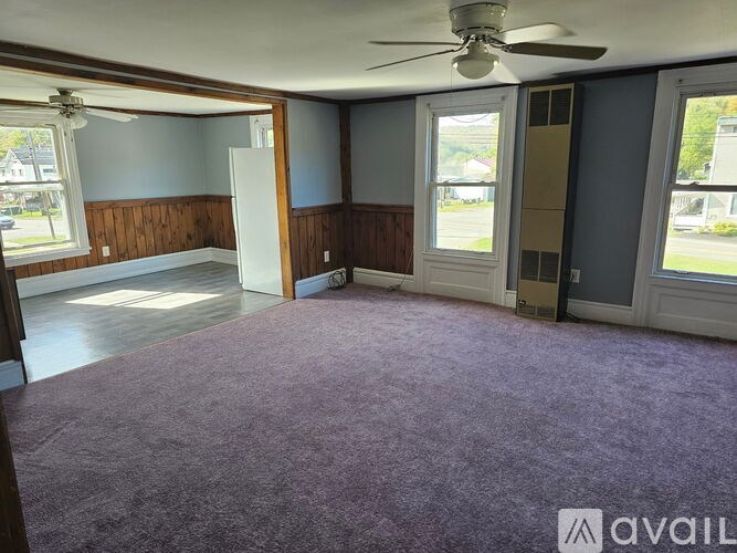 A room with a purple carpet and a ceiling fan.