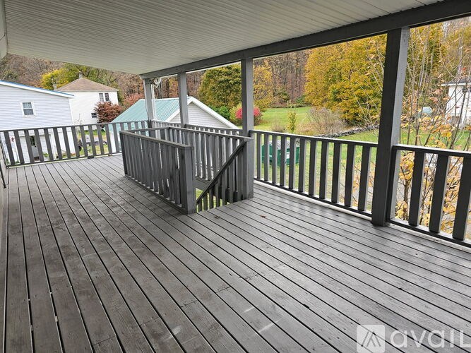 A wooden deck with a metal railing and a white house in the background.
