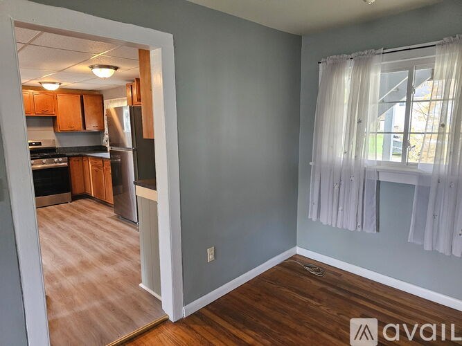 A kitchen with wooden floors and a window with curtains.