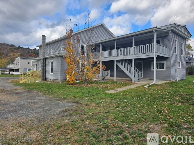 A two-story house with a grey exterior and a balcony on the upper floor.