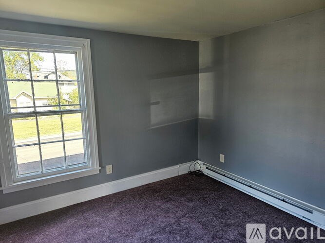 A room with a window and a purple carpet.