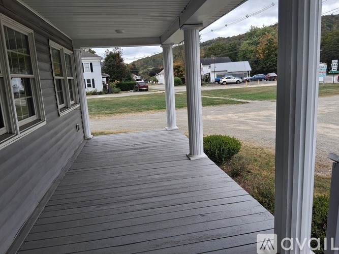 A porch with a view of a parking lot and buildings.