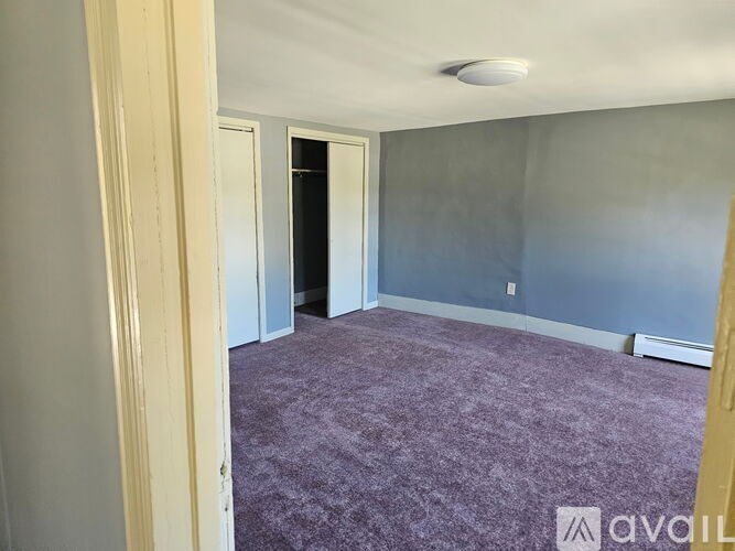 A room with purple carpet and a door in the background.