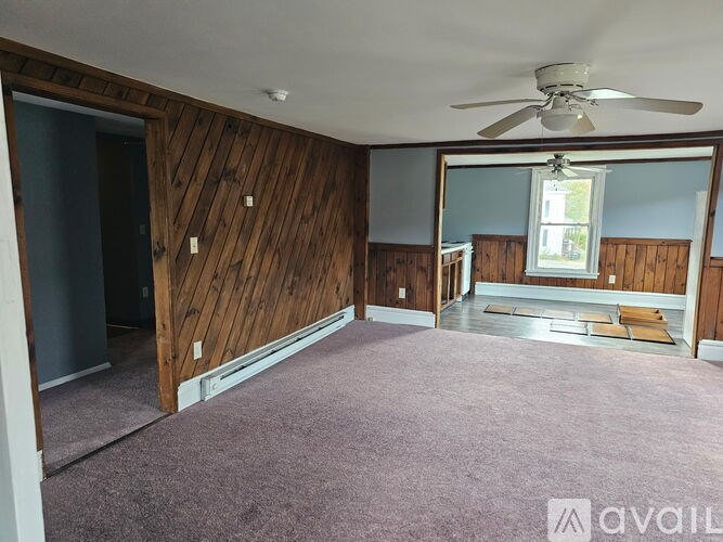 A room with a carpeted floor and a ceiling fan.