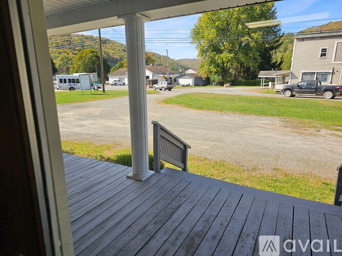 A view from a porch looking out to a parking lot and houses.