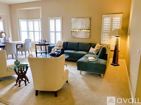 A living room with a green couch and a white chair.